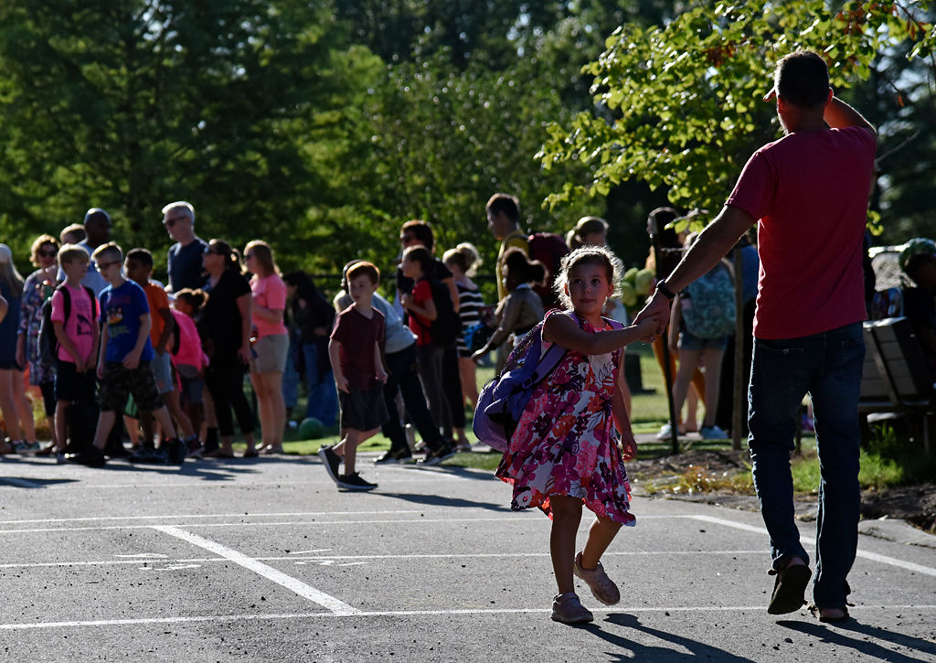 Millie Luther, 6 and a half, looks back at other arriving students while walking with her father